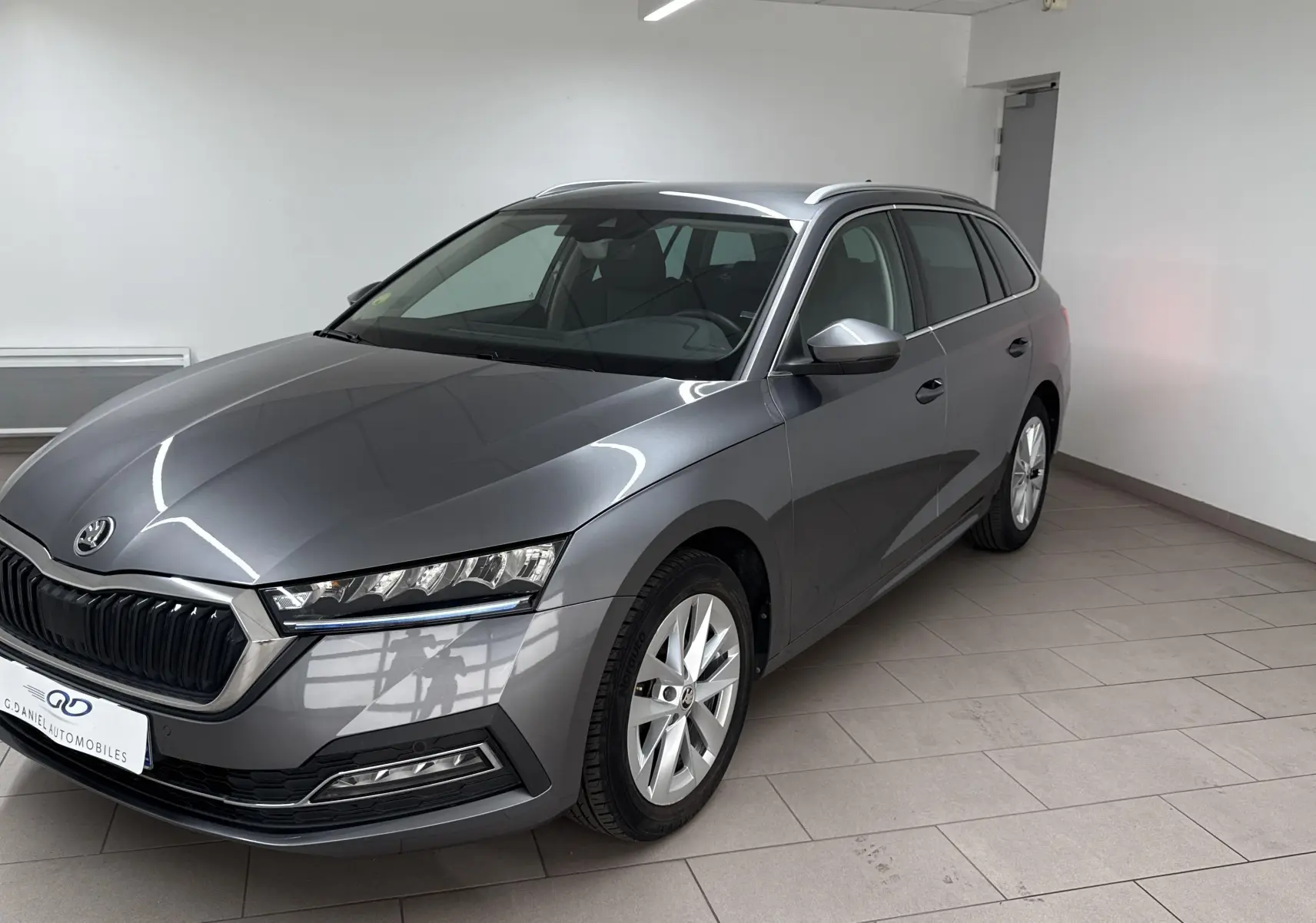 Skoda Octavia Combi gris graphite vue 3/4 avant droit dans un intérieur épuré, finition Style 2023.