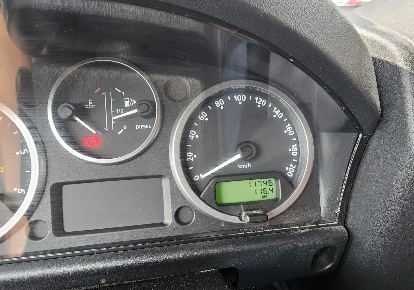 Gros plan sur le tableau de bord noir du Land Rover Defender 90 Diesel 2013, affichant compteur et témoins lumineux.