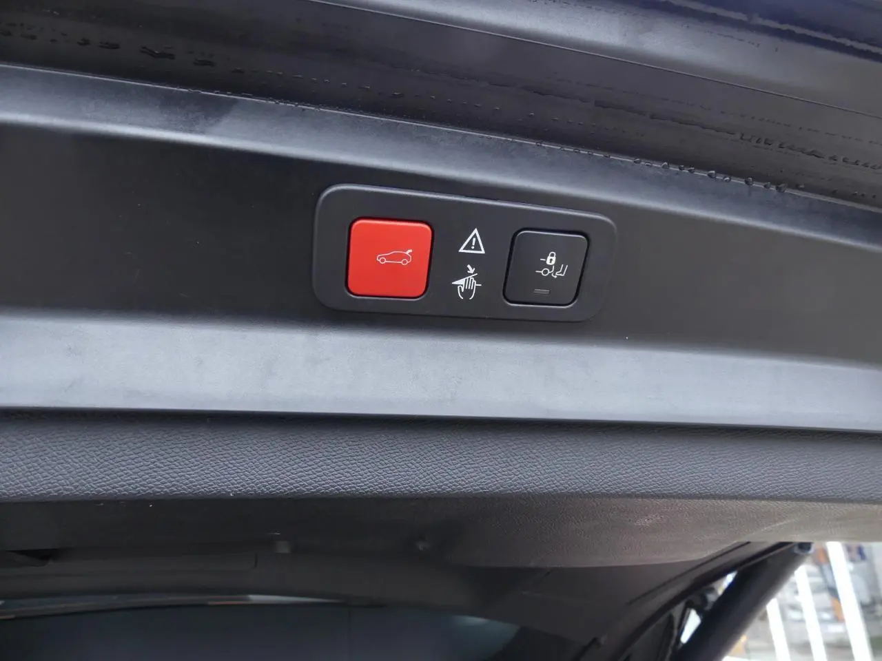 Boutons de commande du hayon motorisé avec accès mains libres sur le coffre d'un Peugeot 5008 noir métallisé, vue intérieure du hayon.