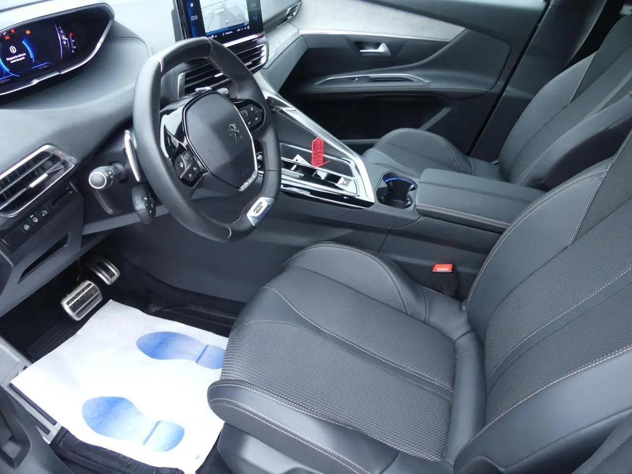 Vue intérieure côté conducteur du Peugeot 5008 GT 2023, avec sièges noirs et volant compact multifonctions cuir perforé.