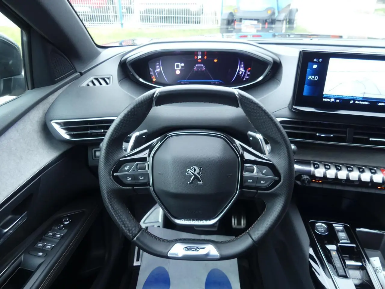 Vue intérieure centrée sur le volant cuir perforé GT et le combiné numérique du Peugeot 5008 noir métallisé 2023.