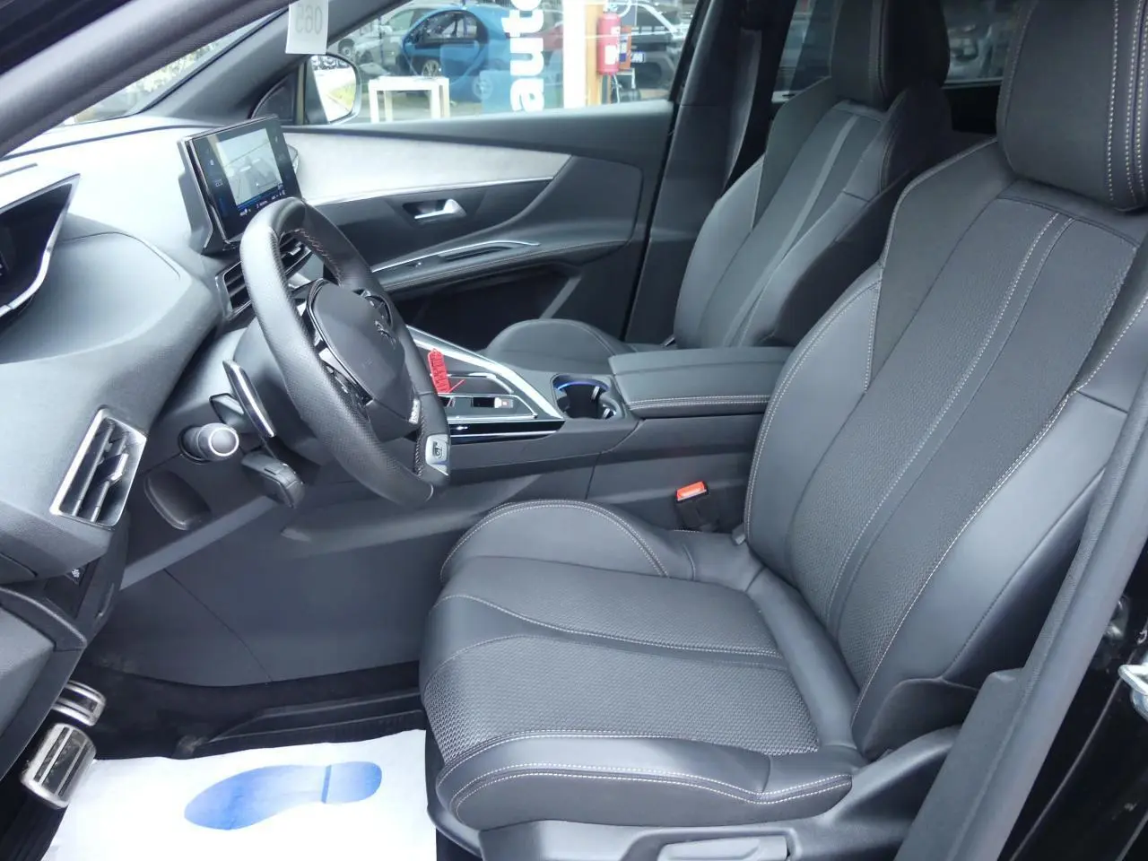 Intérieur avant droit du Peugeot 5008 GT 2023 noir métallisé avec sièges cuir noirs et volant compact multifonctions.