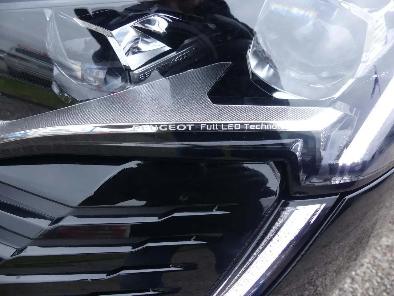 Gros plan sur le phare avant droit noir métallisé du Peugeot 5008 2023 avec signature Full LED et calandre GT chromée.