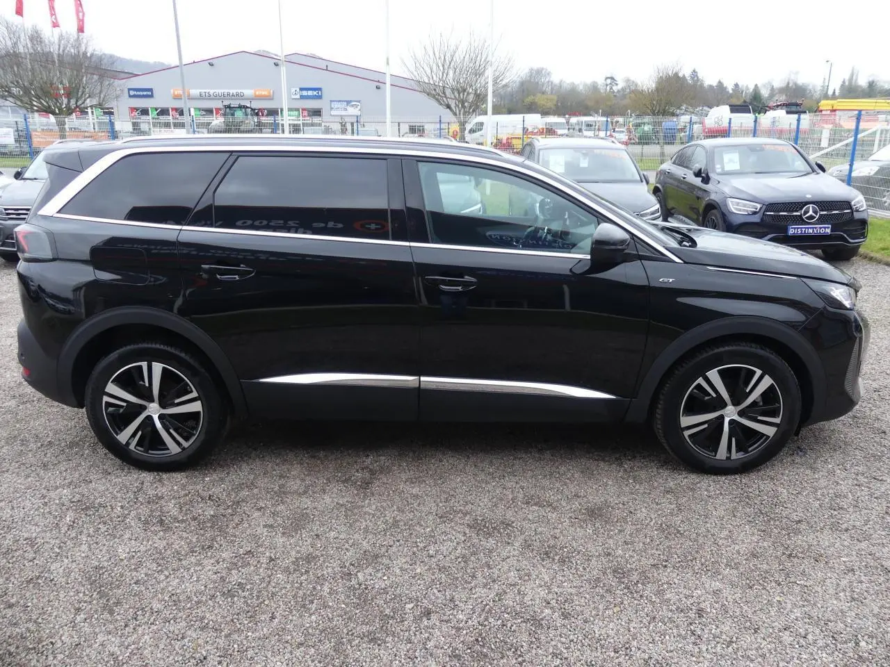 Profil côté droit du Peugeot 5008 GT 2023 noir métallisé avec jantes bi-ton et vitres arrière surteintées.