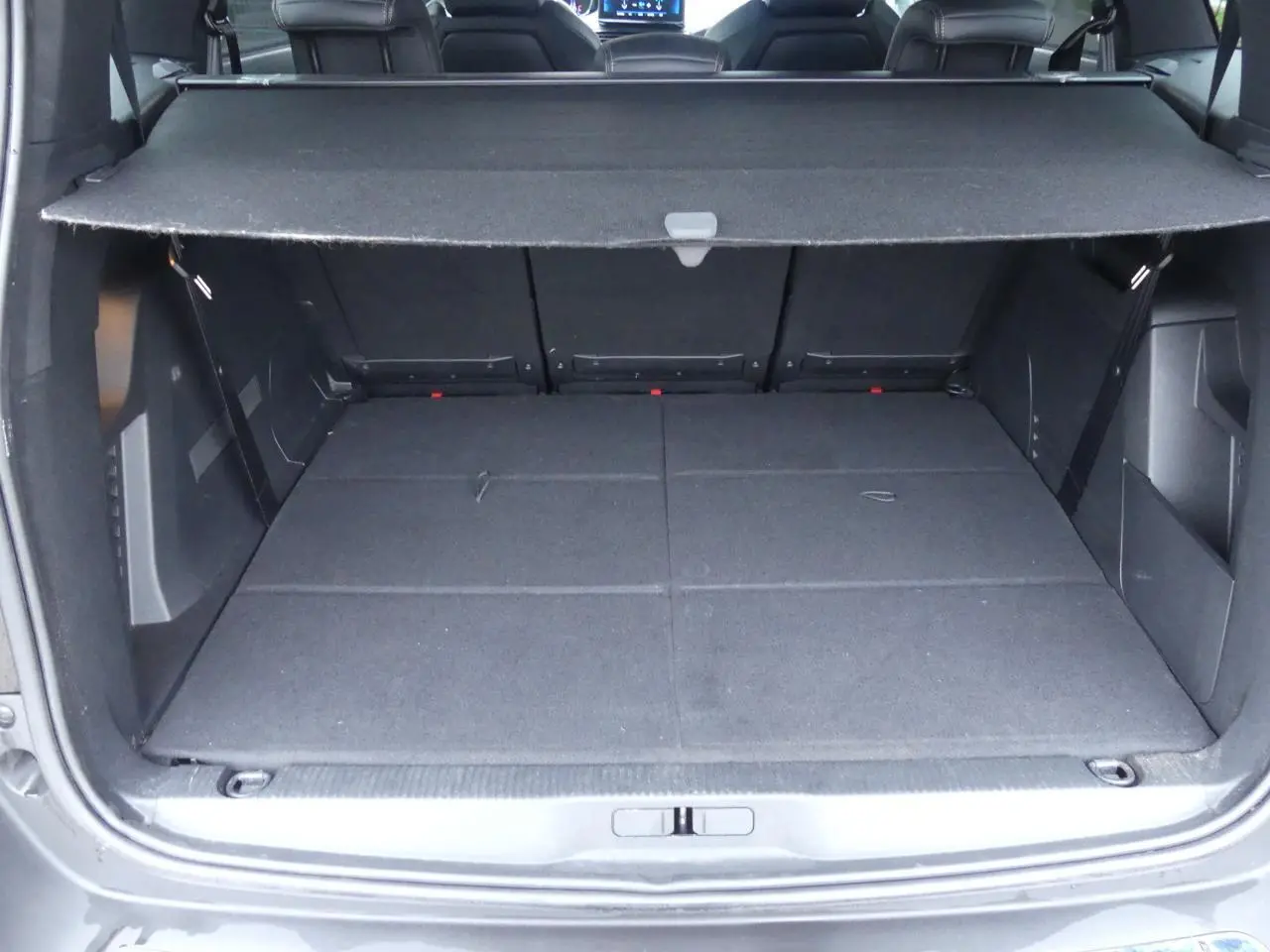 Coffre ouvert du Peugeot 5008 GT noir métallisé, montrant l'espace de chargement avec cache-bagages déployé.