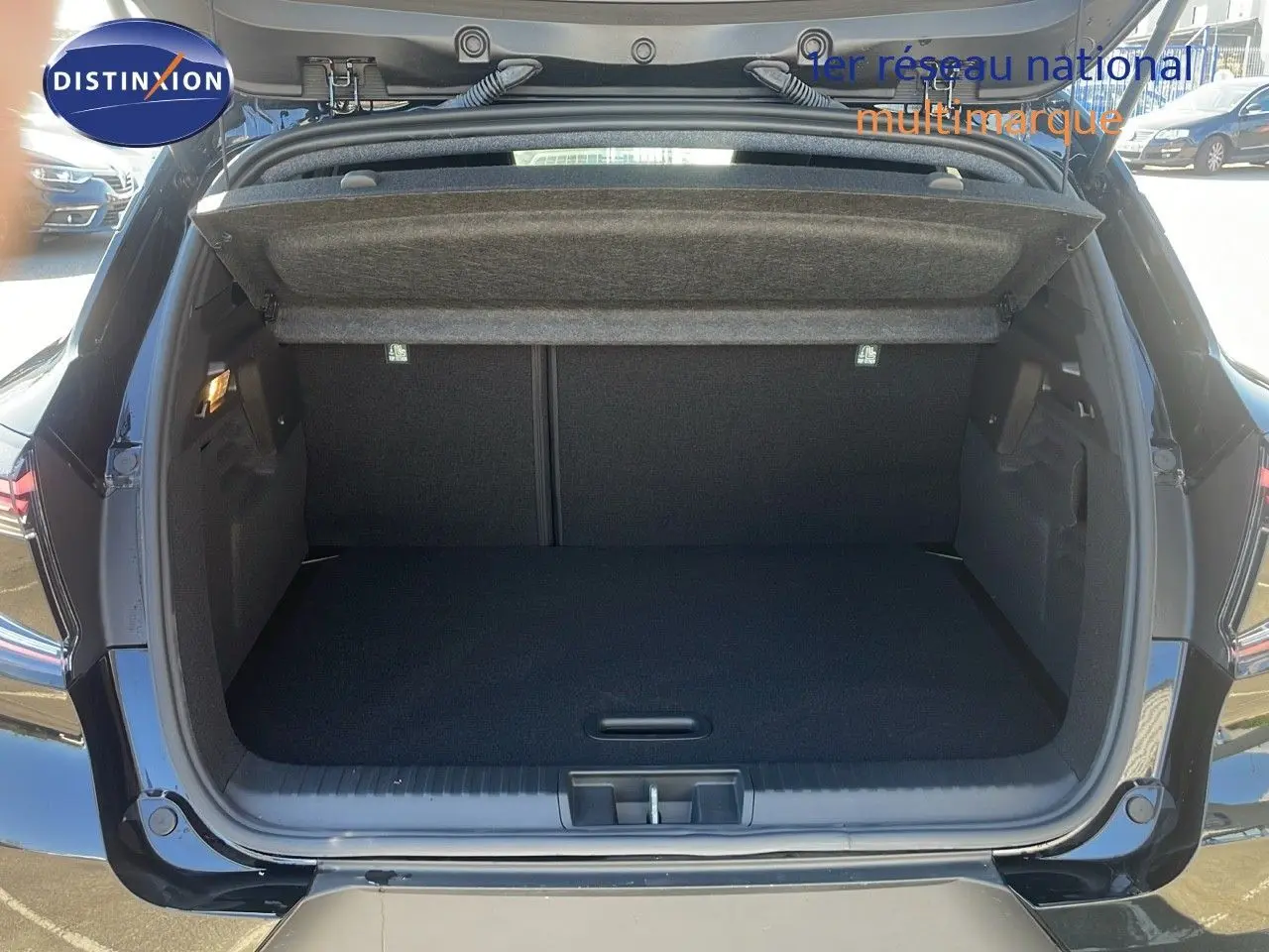 Coffre ouvert d'un Renault Captur noir étoile métal, vue arrière montrant l'espace de rangement vide et la plage arrière relevée.