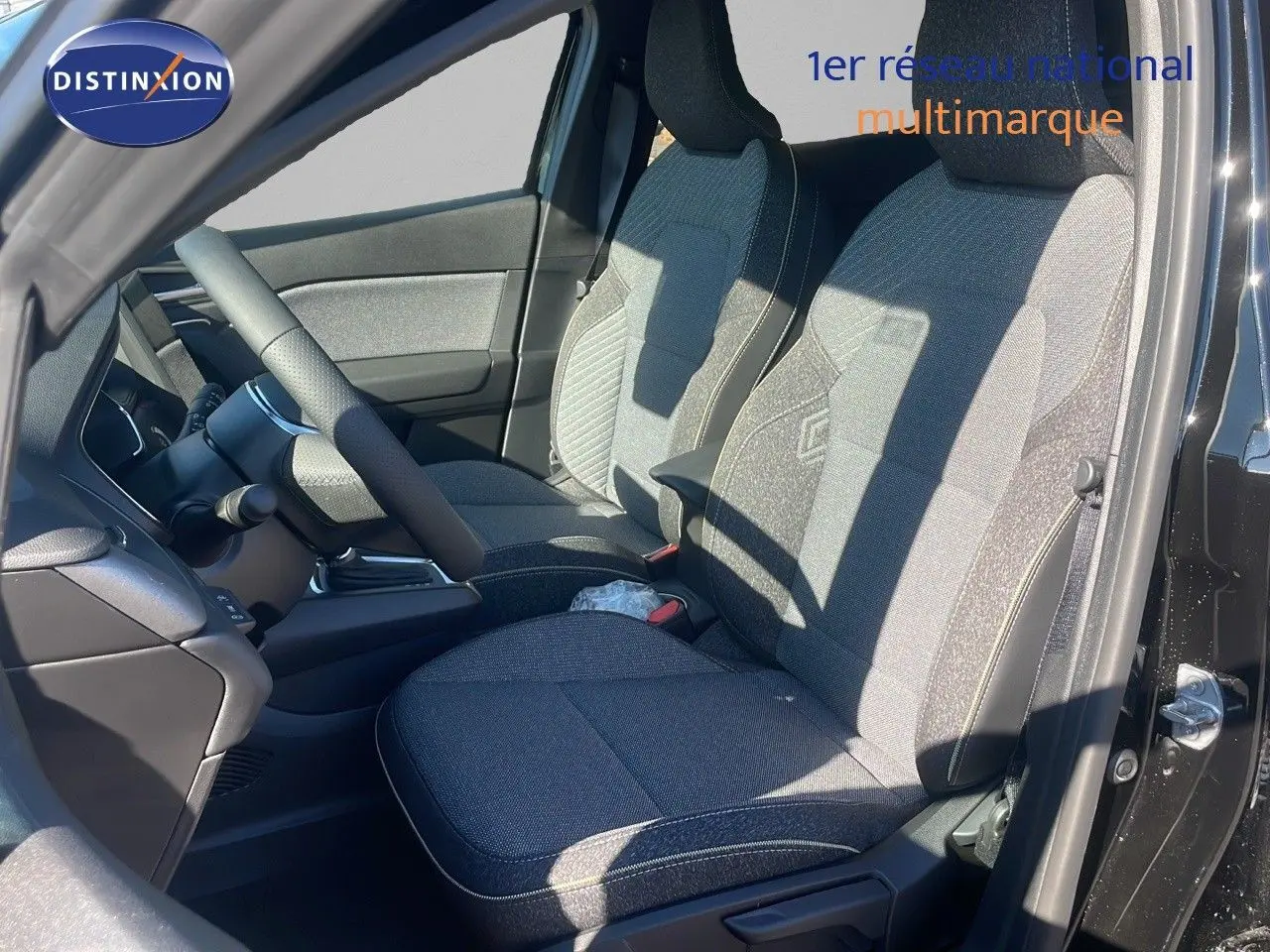 Intérieur du Renault Captur E-Tech hybride 2025, vue côté gauche sur les sièges tissu gris et volant noir.