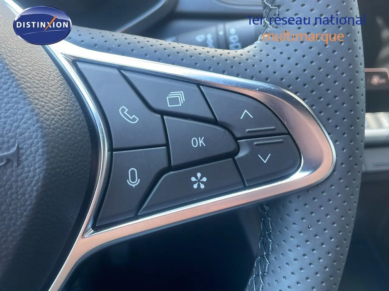 Gros plan sur les commandes multifonctions du volant en cuir perforé du Renault Captur E-Tech hybride noir étoile métal 2025.