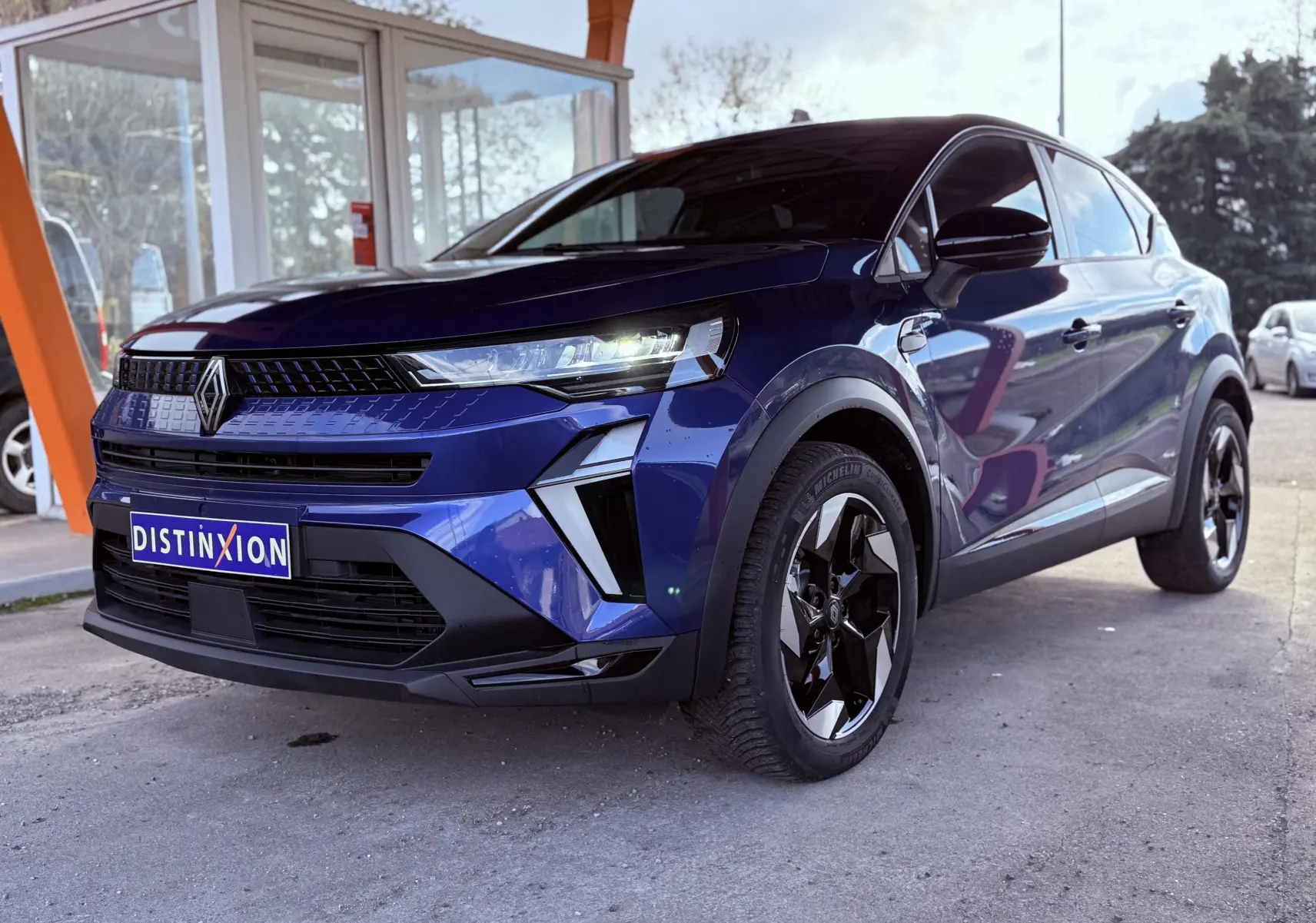 Renault Captur E-Tech hybride 2025 bleu Iron Metal avec toit noir, vu en 3/4 avant droit sous abri.