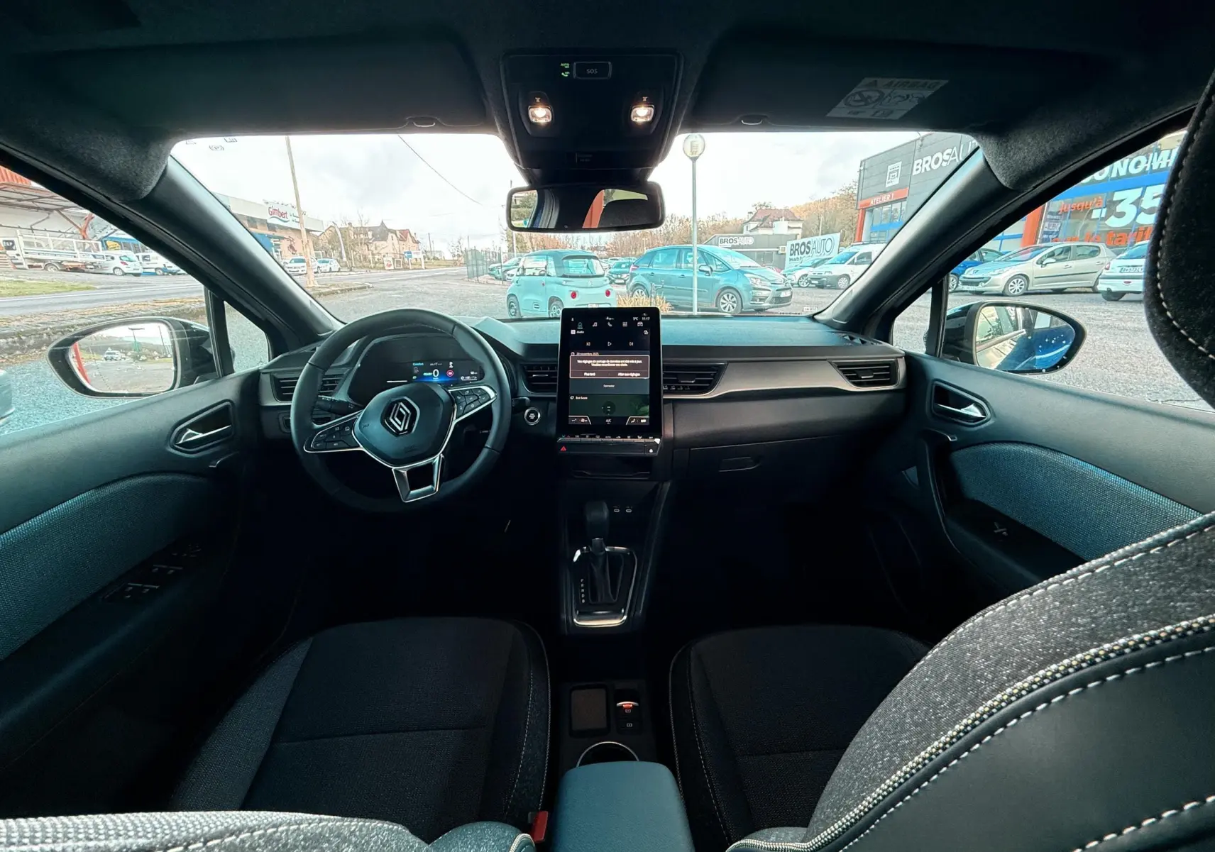 Intérieur du Renault Captur E-Tech hybride 2025 vu de l'arrière, avec tableau de bord moderne et écran tactile vertical.