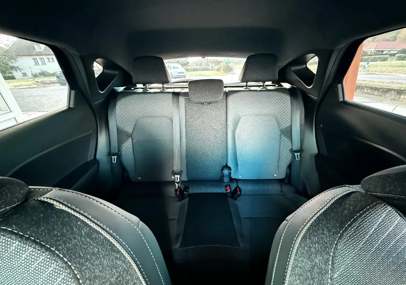 Vue arrière intérieure du Renault Captur 2025 montrant les sièges arrière en tissu gris avec ceintures de sécurité.