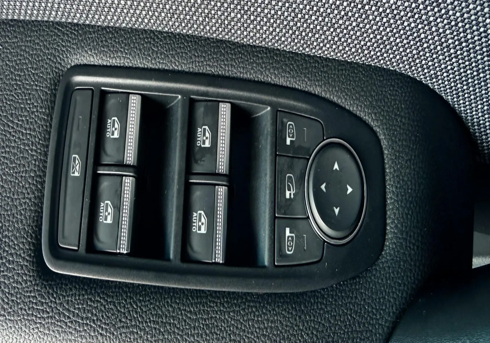 Gros plan sur les commandes des vitres et rétroviseurs côté conducteur du Renault Captur bleu Iron Metal avec toit noir 2025.