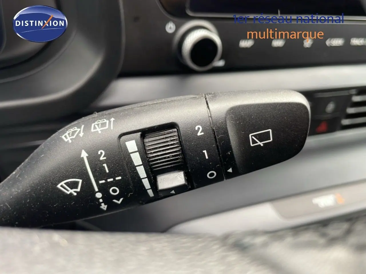 Gros plan sur la commande d'essuie-glace noire du Hyundai i20 2025, intérieur sombre avec détails blancs visibles.