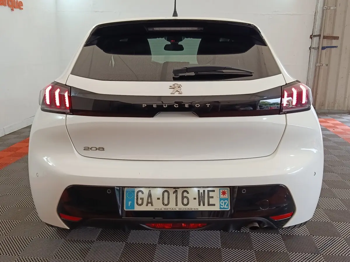Vue arrière d'une Peugeot 208 blanche de 2021 avec feux LED allumés et plaque d'immatriculation française.