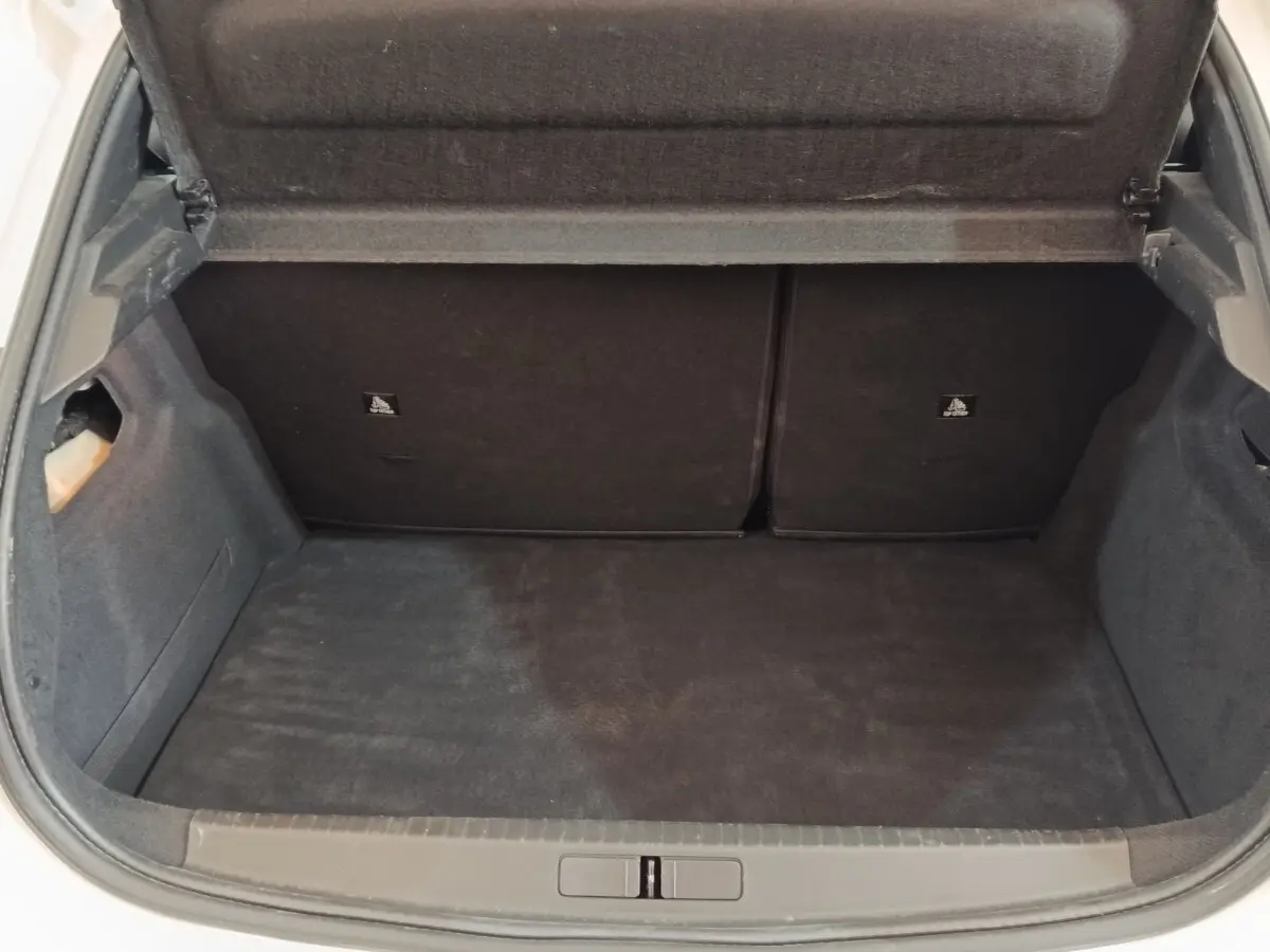 Coffre ouvert de la Peugeot 208 blanc vue de l'arrière, montrant l'espace de chargement et la banquette rabattable.