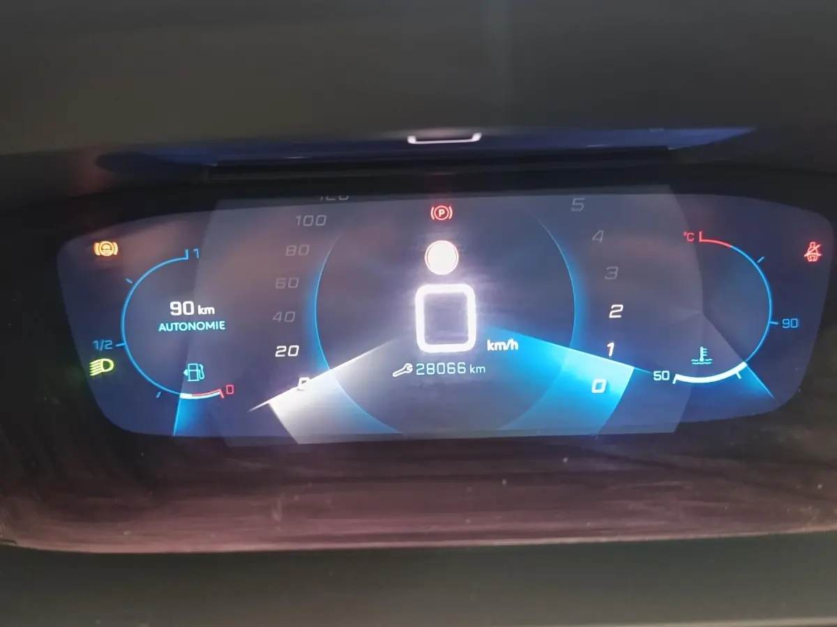 Affichage numérique du tableau de bord de la Peugeot 208 blanc, montrant la vitesse à 0 km/h et l'autonomie à 90 km.