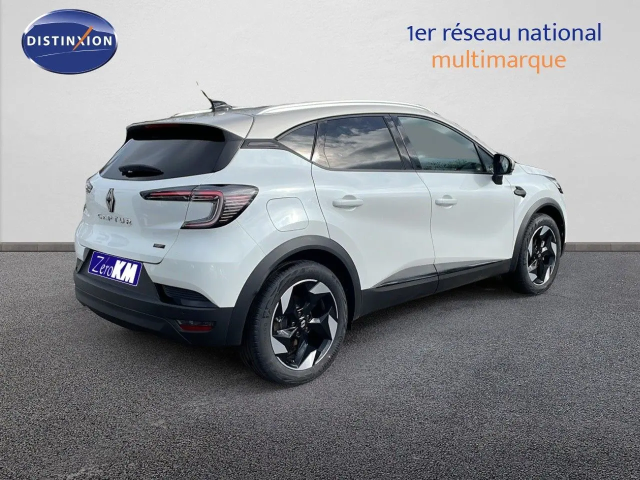 Vue 3/4 arrière droite d'un Renault Captur blanc nacré avec toit beige et jantes noires distinctives.