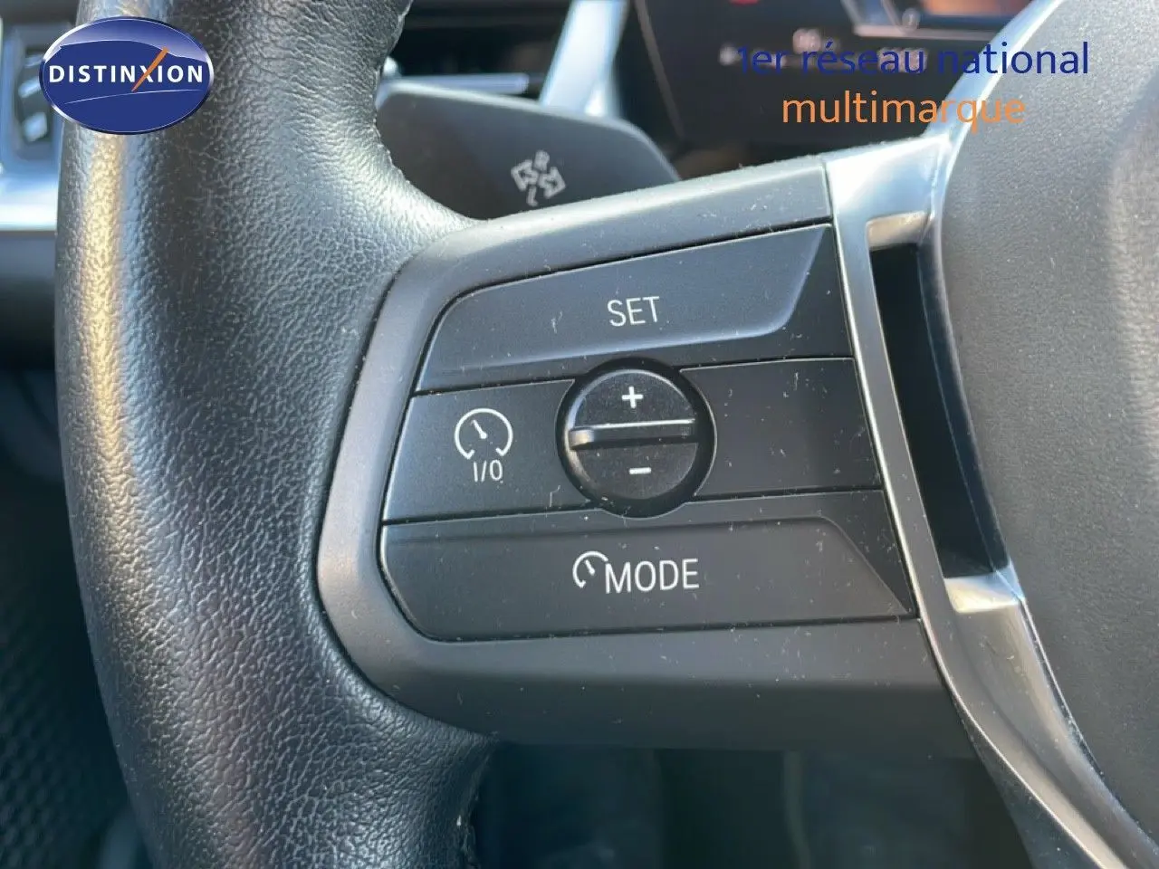 Gros plan sur les commandes de régulateur de vitesse au volant d’une BMW Série 2 Active Tourer 218i bleu phytonique.