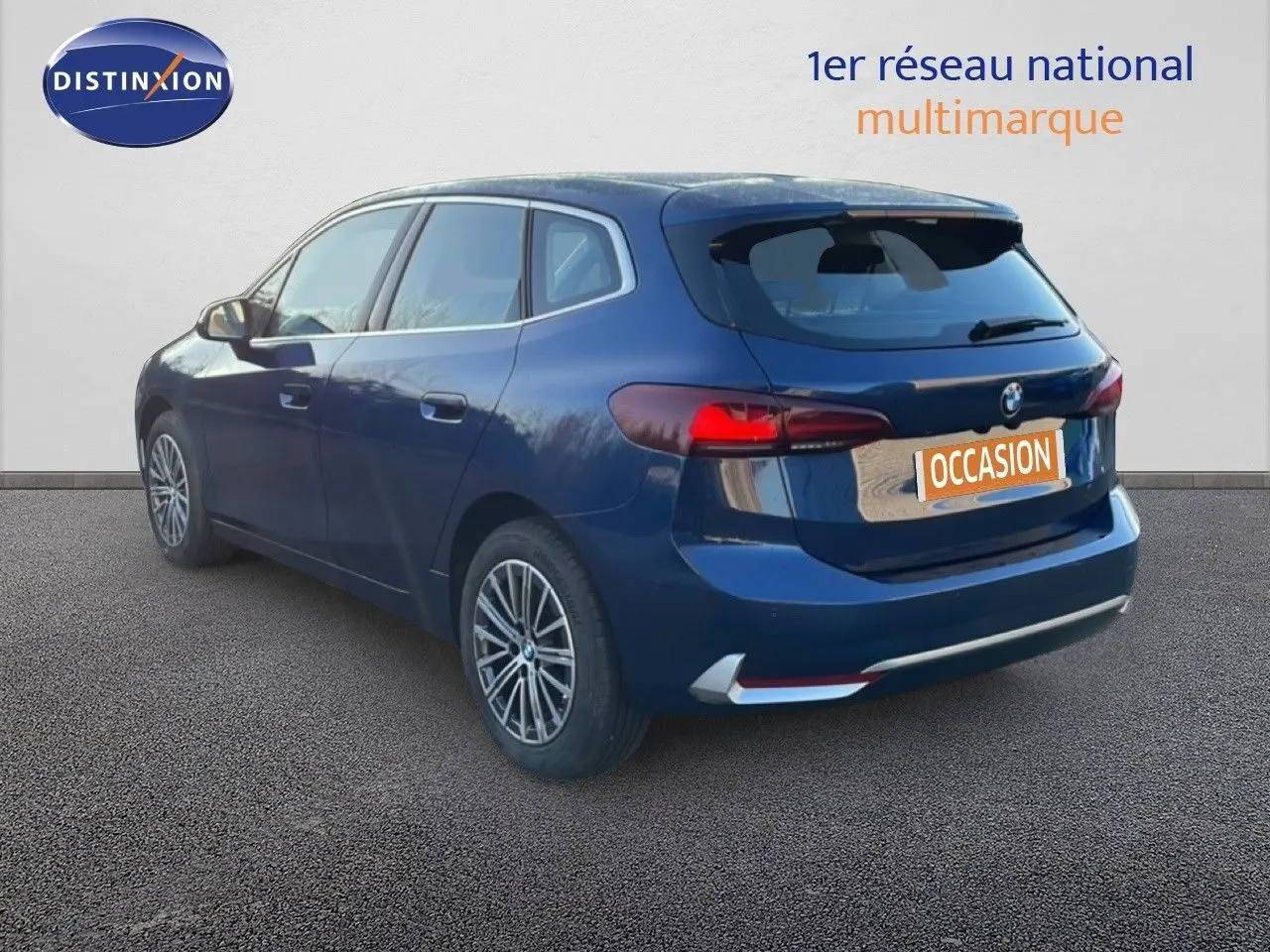 BMW Série 2 Active Tourer 218i bleu phytonique métal vue 3/4 arrière droit avec feux arrière allumés.