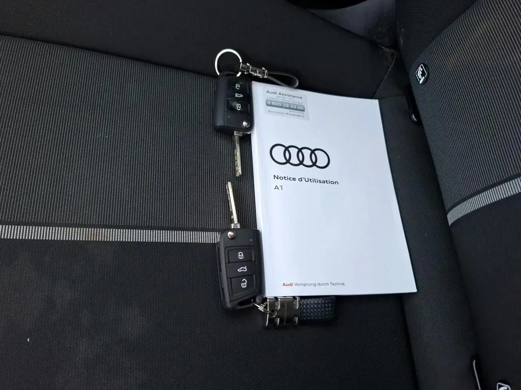 Vue intérieure côté conducteur de l'Audi A1 2022 avec sièges tissu noirs et volant cuir multifonctions.
