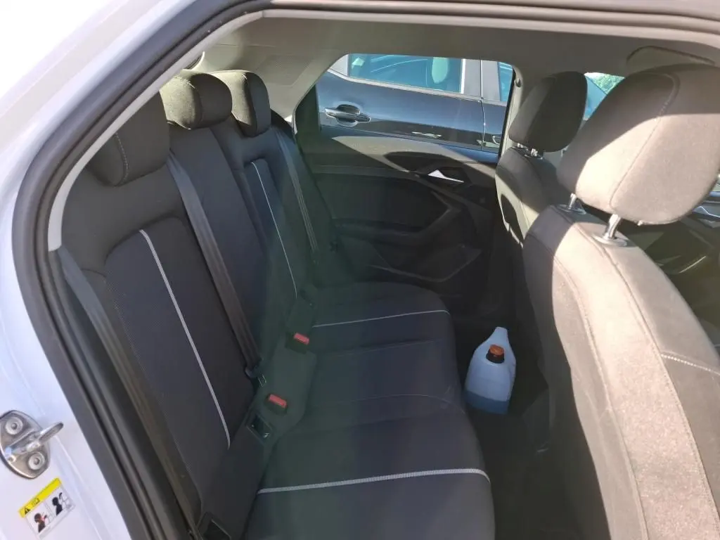 Gros plan sur la commande de lève-vitre côté gauche d’une Audi A1 blanche, intérieur noir texturé.