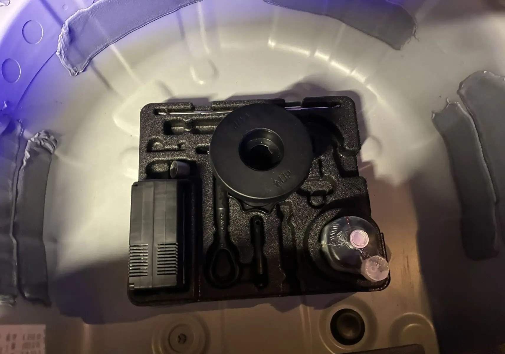 Vue rapprochée du coffre d’une Audi A1 blanche 2022 montrant le kit de réparation crevaison rangé dans la roue de secours.