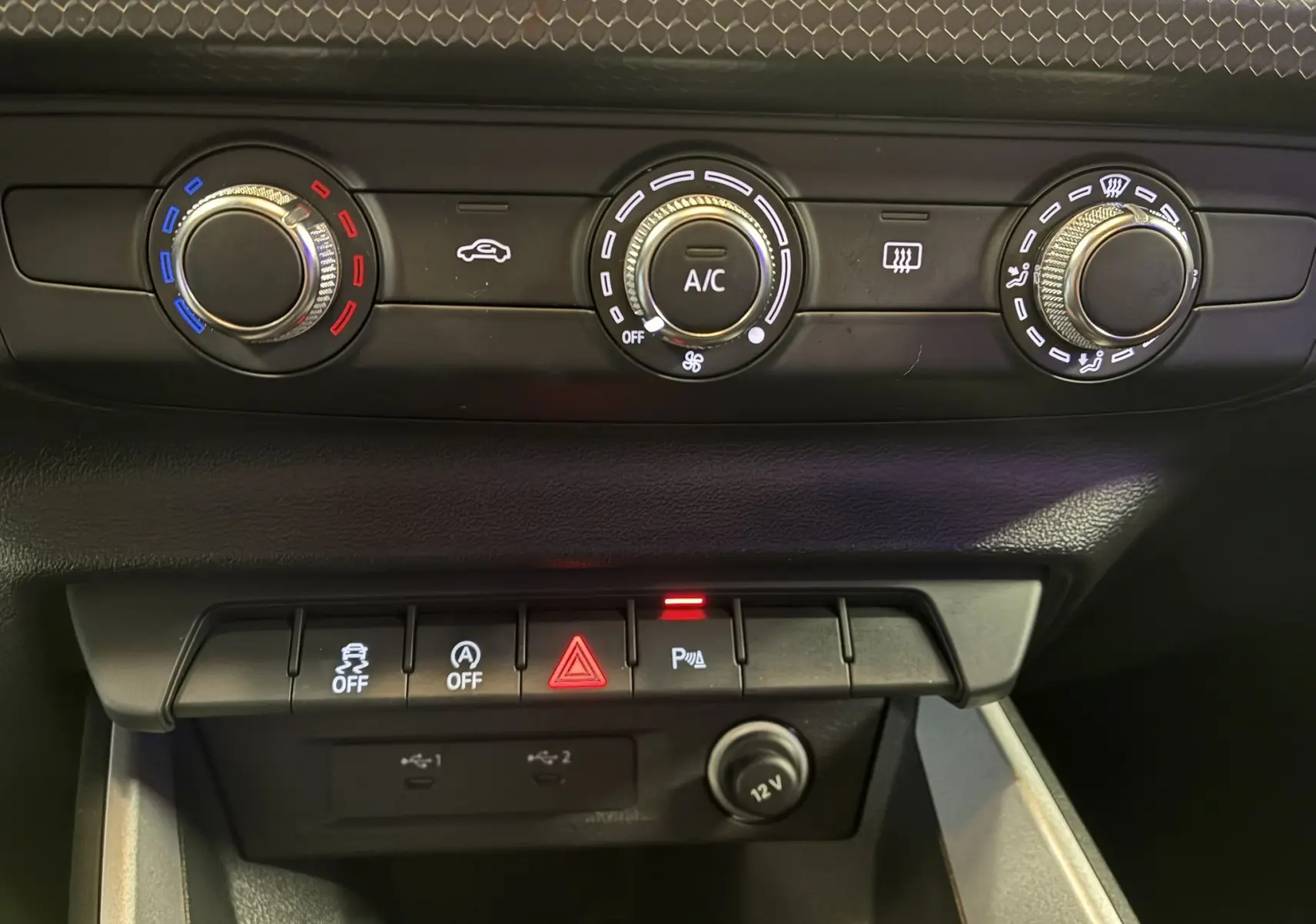 Gros plan sur les commandes de climatisation et les boutons de fonction d'une Audi A1 blanche, intérieur noir.