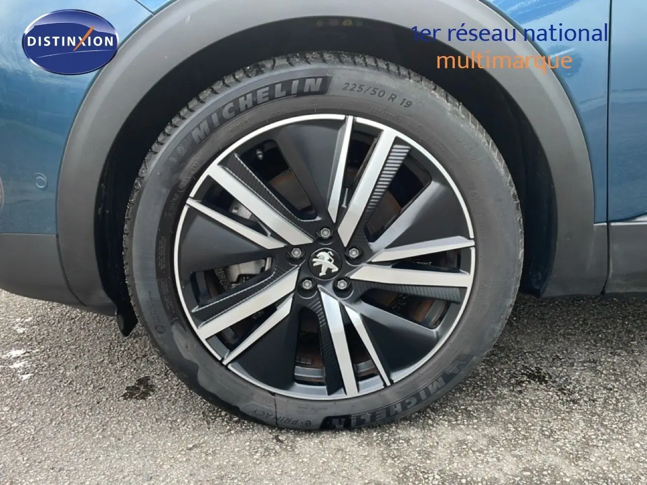 Gros plan sur la roue avant droite d’un Peugeot 3008 bleu Célèbes Métal avec jante alliage noire et argent.