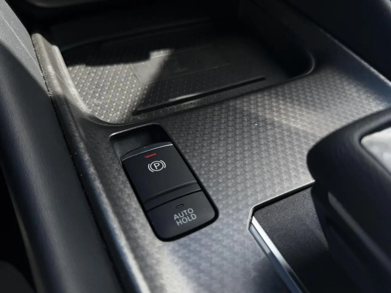 Gros plan sur la commande de frein à main électrique et fonction Auto Hold dans le console centrale du Nissan Qashqai blanc nacré.