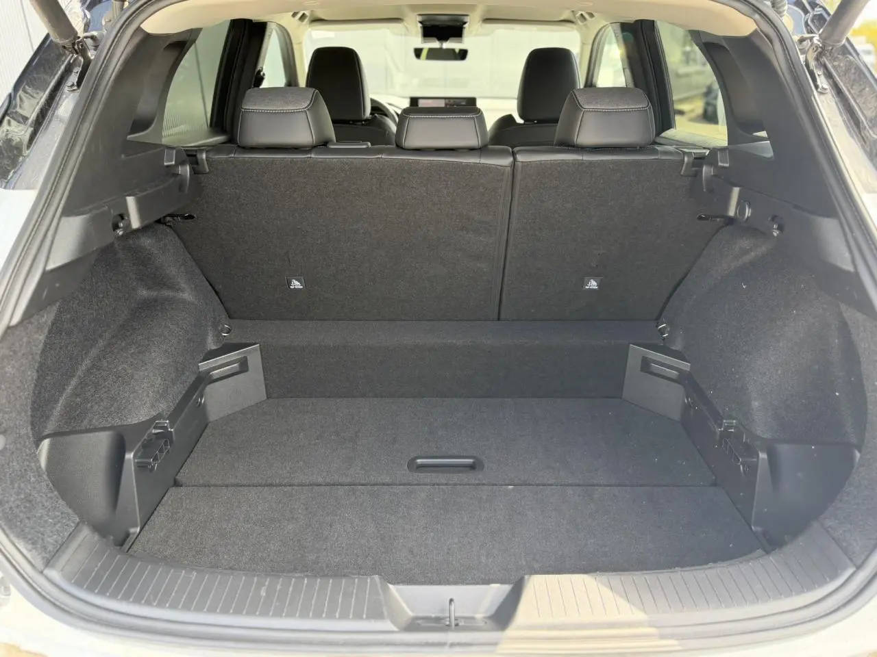 Coffre spacieux du Nissan Qashqai blanc nacré vu de l'arrière avec banquette arrière noire et plancher modulable.