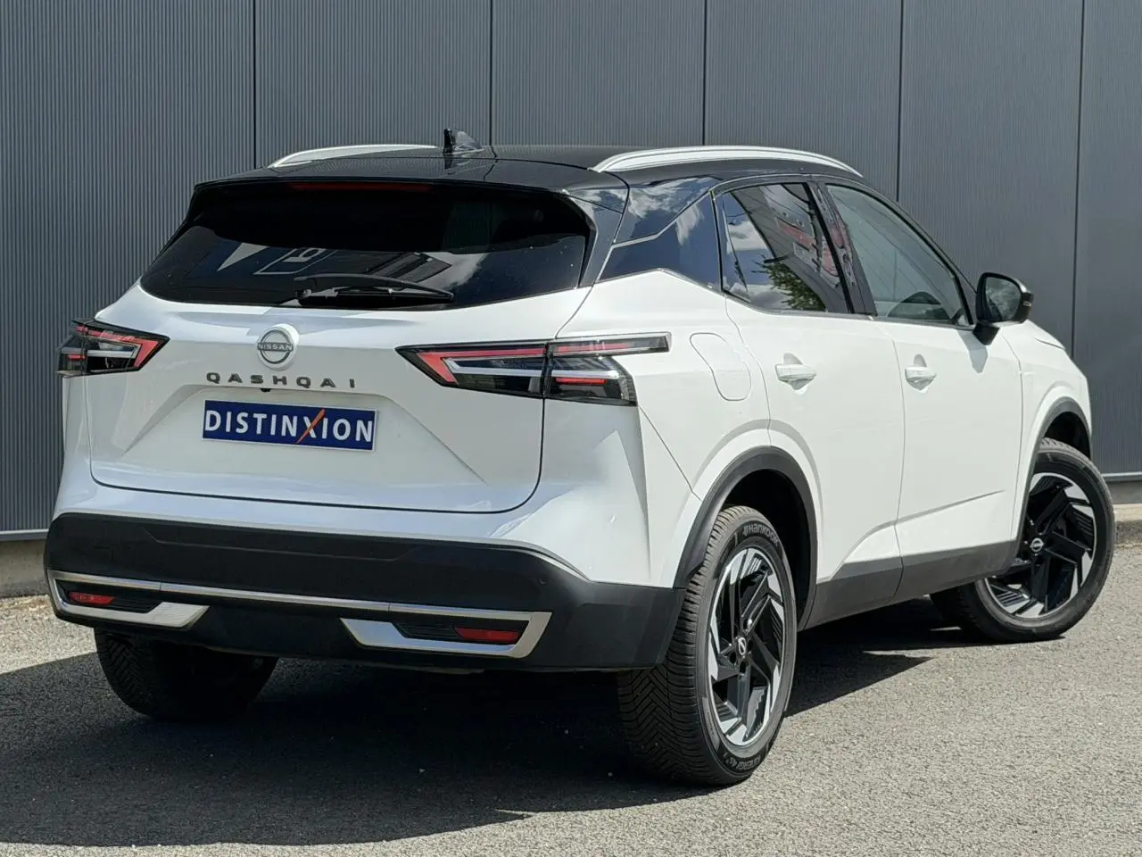 Vue 3/4 arrière droite du Nissan Qashqai blanc nacré avec toit noir et jantes alliage noires.