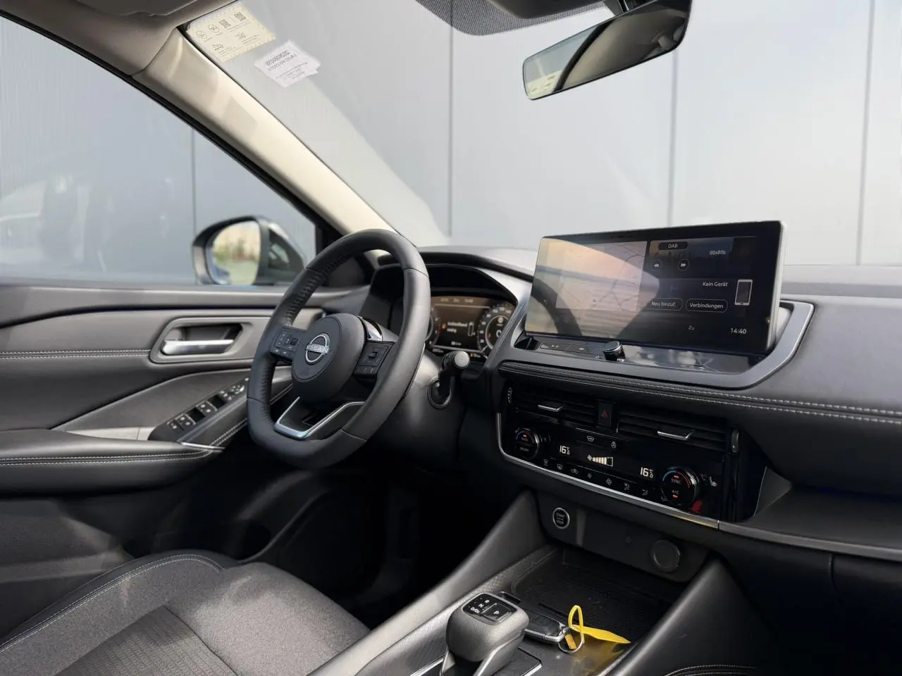 Intérieur côté conducteur du Nissan Qashqai 2025 avec tableau de bord noir, écran tactile et volant cuir multifonction.