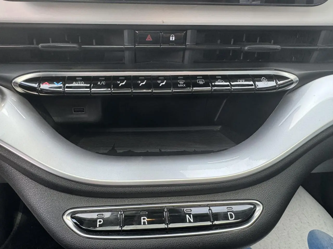 Vue rapprochée de la console centrale blanche de la Fiat 500 électrique 2022, avec commandes climatisation et boîte auto.