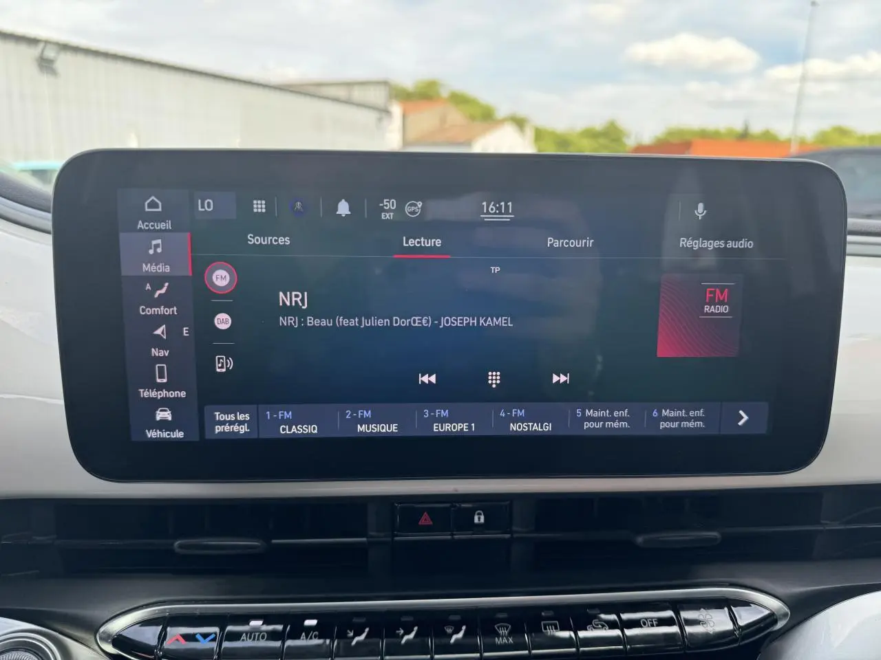 Écran tactile central de la Fiat 500 électrique 2022 affichant la radio NRJ avec commandes multimédia et climatisation en dessous.