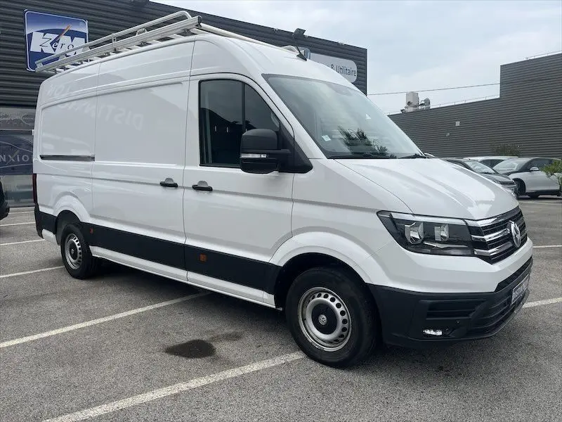 Vue 3/4 avant droit d'un Volkswagen Crafter fourgon blanc avec galerie de toit, stationné en extérieur.