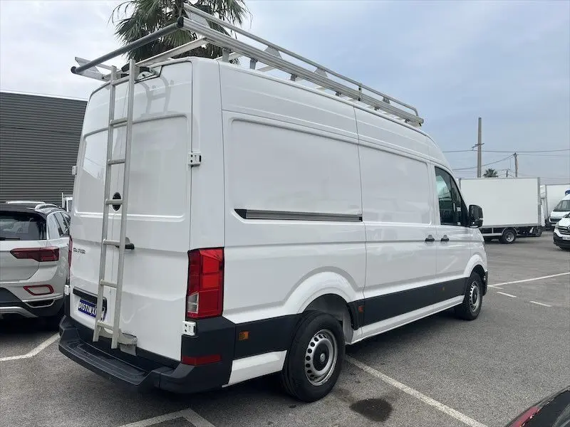 Vue 3/4 arrière droite d'un Volkswagen Crafter fourgon blanc 2019 avec galerie et échelle sur le toit.