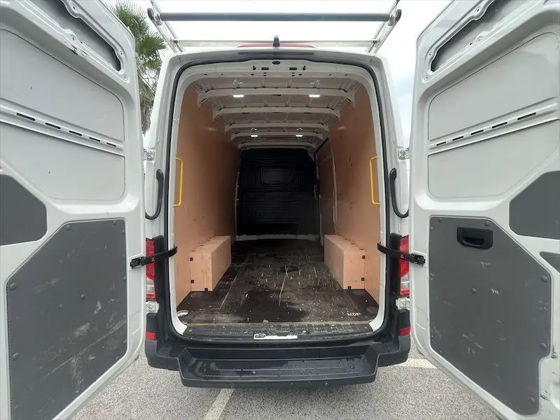 Vue arrière ouverte du Volkswagen Crafter blanc L3H3 Business Line 2019 montrant l'espace de chargement vide avec parois en bois.