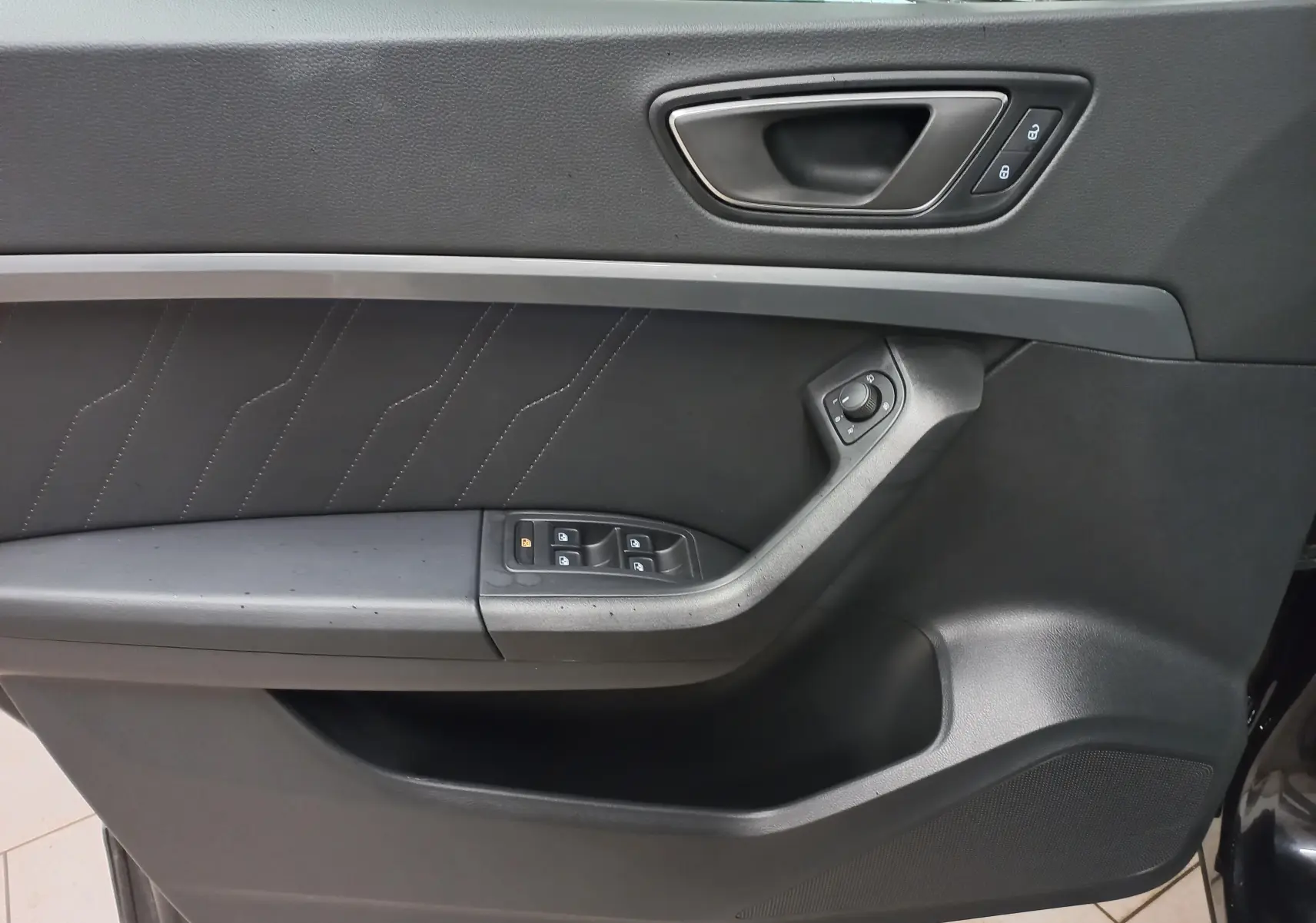 Gros plan sur la porte intérieure côté gauche du SEAT Ateca noir, avec commandes de vitres et verrouillage intégrés.