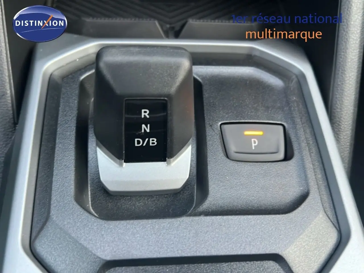 Gros plan sur la commande de boîte automatique et frein de parking électrique du Dacia Duster Hybrid 140 blanc Glacier.