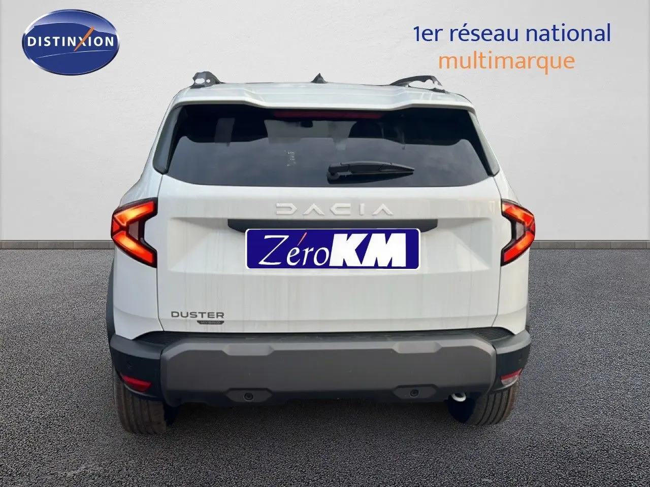 Vue arrière du Dacia Duster Hybrid 140 Journey blanc Glacier avec feux arrière en forme de C et barres de toit visibles.