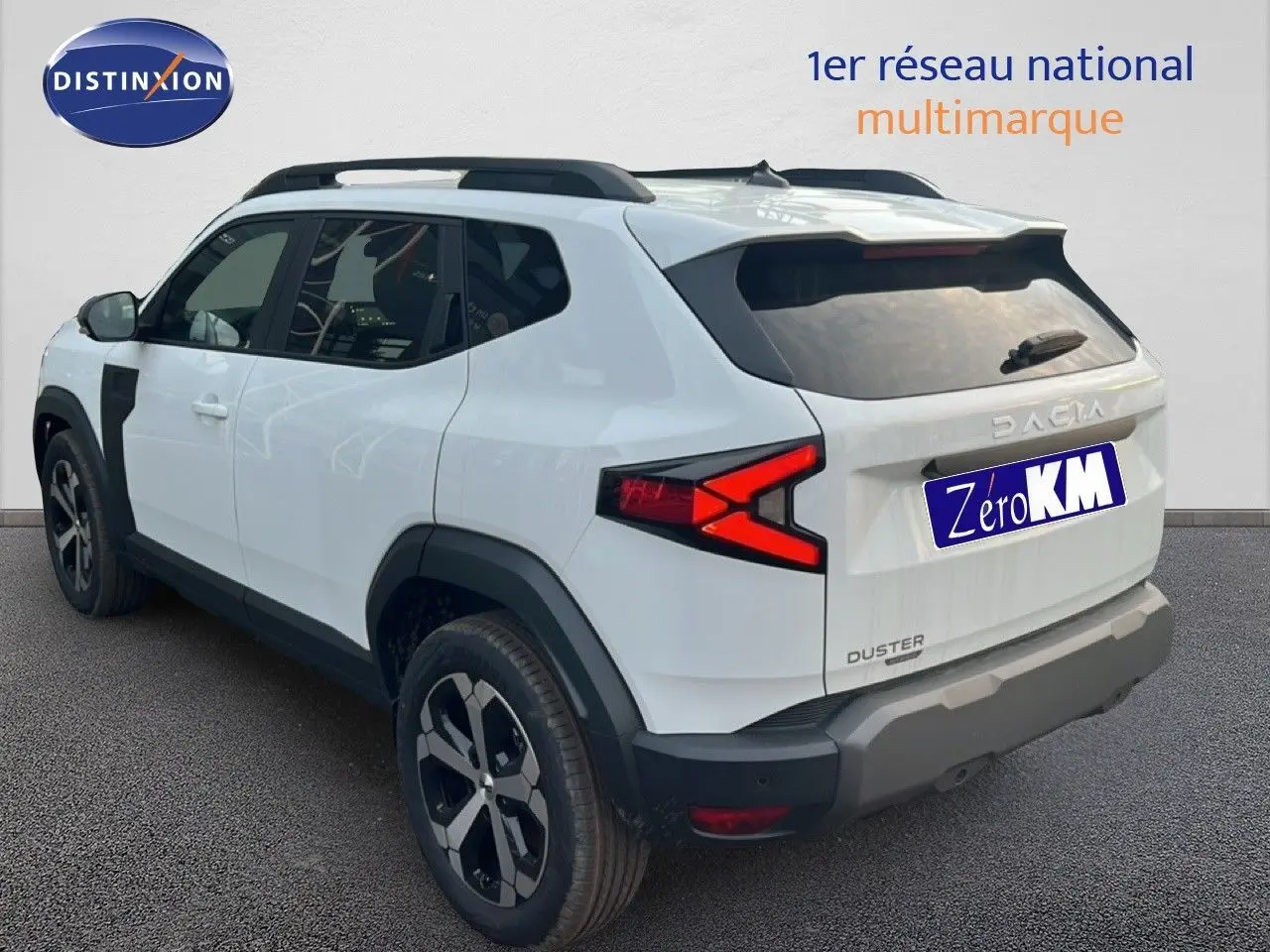 Vue 3/4 arrière droite du Dacia Duster Hybrid 140 blanc Glacier avec jantes alliage 18 pouces et barres de toit.