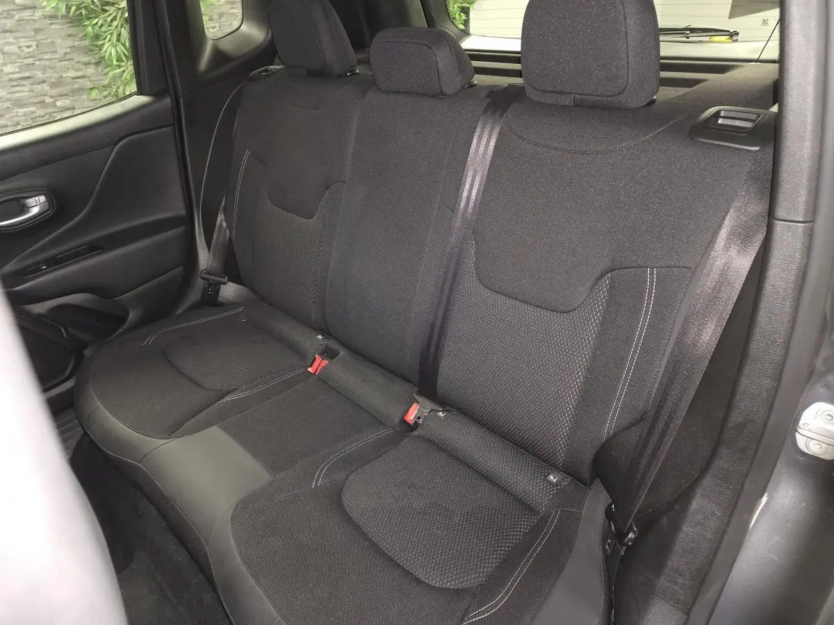 Vue intérieure du siège arrière en tissu noir du Jeep Renegade 2024, avec ceintures de sécurité visibles.