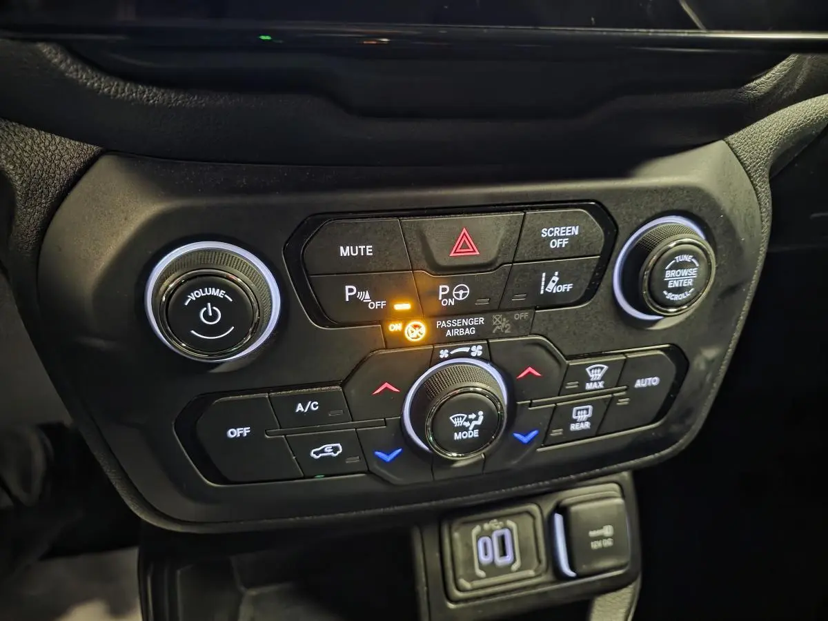 Panneau de commande central noir du Jeep Renegade 2024 avec boutons de climatisation et aides au stationnement allumés