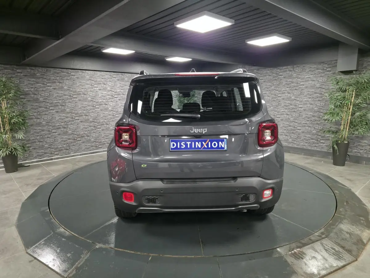 Vue arrière du Jeep Renegade gris métallisé avec toit noir, feux LED et logo distinctif sur un plateau tournant.