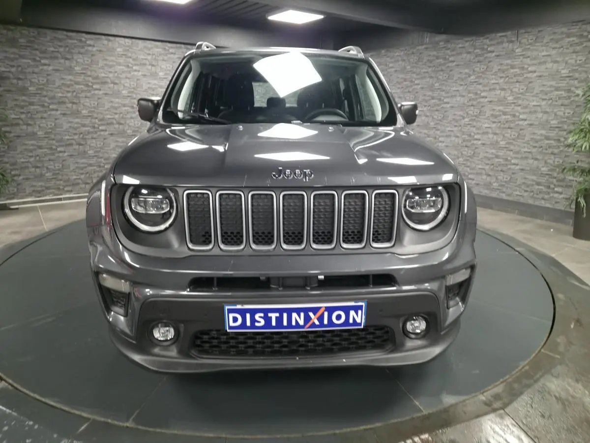 Vue avant d'un Jeep Renegade gris métallisé avec calandre noire et feux LED ronds dans un showroom.