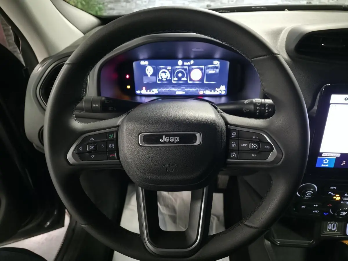 Vue rapprochée du volant Jeep Renegade 2024 avec commandes intégrées et tableau de bord numérique lumineux.