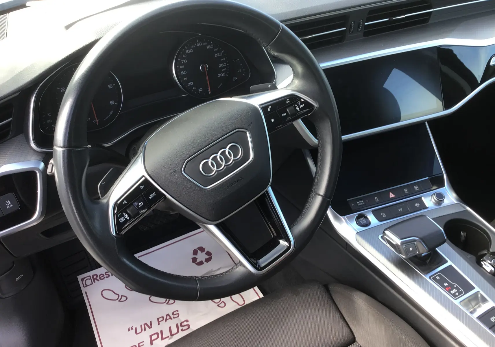 Vue intérieure centrée sur le volant Audi avec commandes multifonctions et tableau de bord numérique de l'Audi A6 Avant.