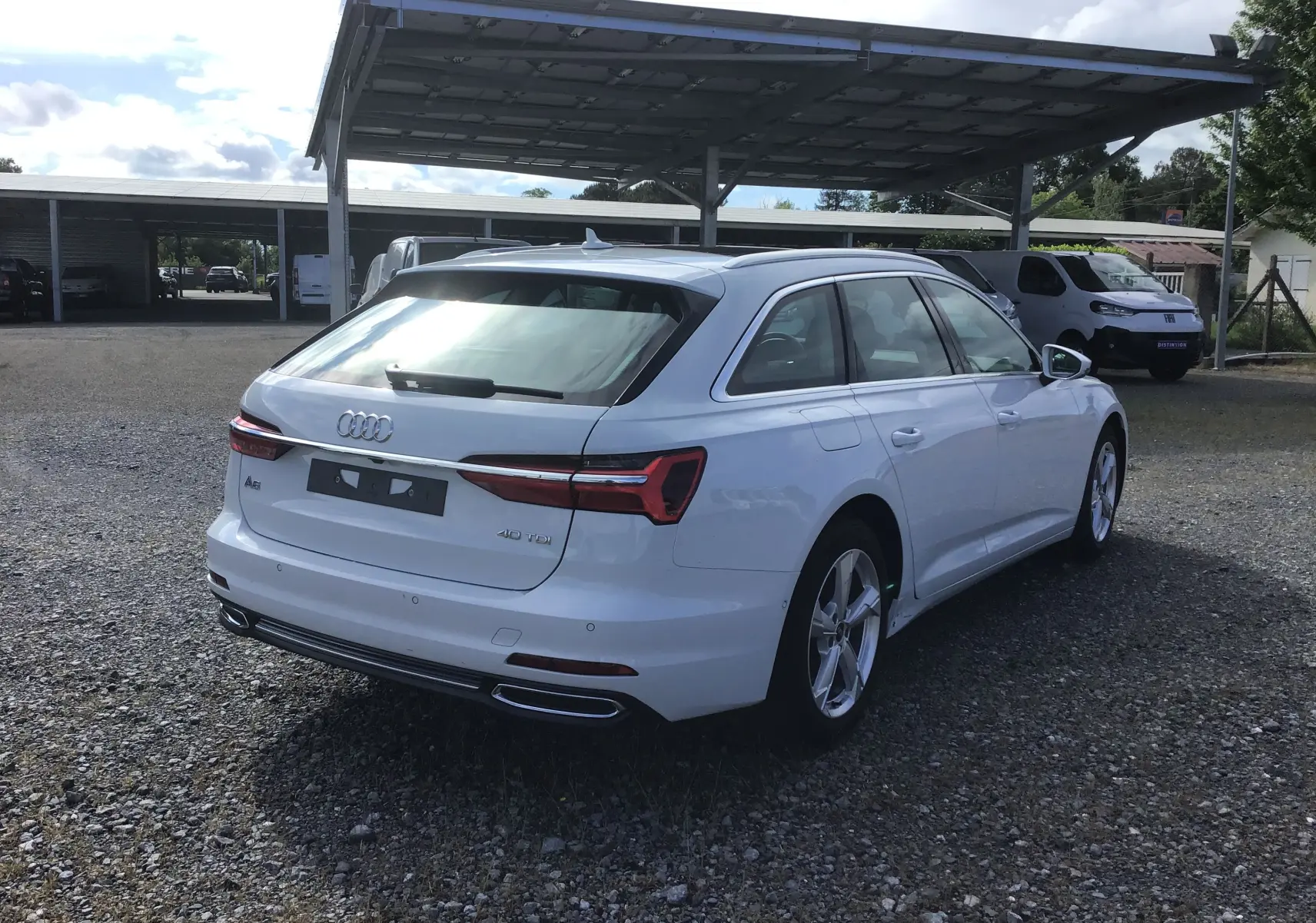 Audi A6 Avant blanc glacier vue 3/4 arrière droit, avec feux LED et double sortie d’échappement chromée.