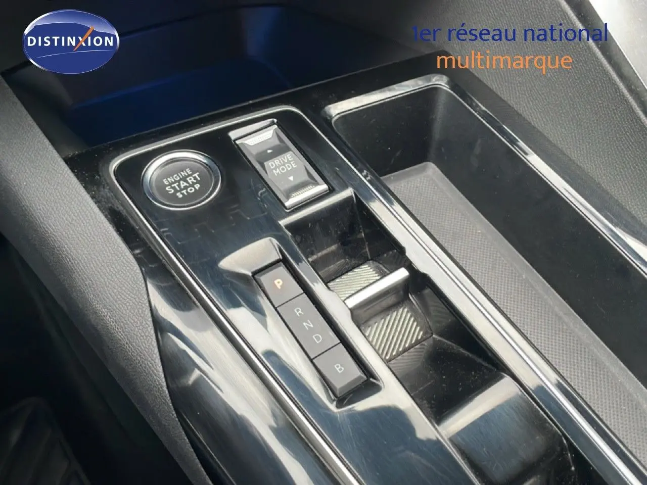 Gros plan sur la console centrale noire brillante du Peugeot 3008 hybride avec boutons start/stop et sélection mode de conduite.