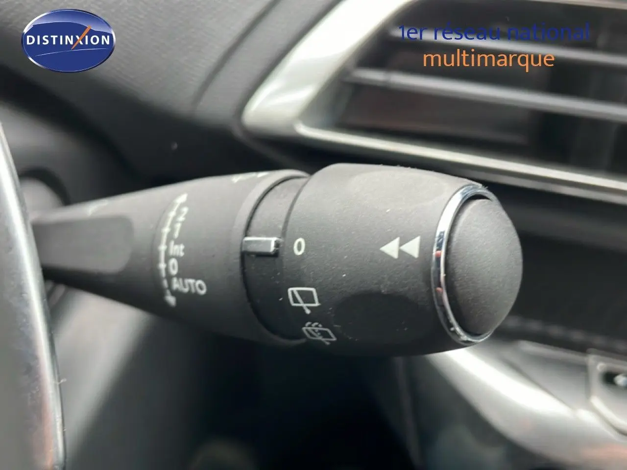 Gros plan sur la commande d’essuie-glace à gauche du volant dans l’habitacle noir du Peugeot 3008 hybride gris Artense 2024.
